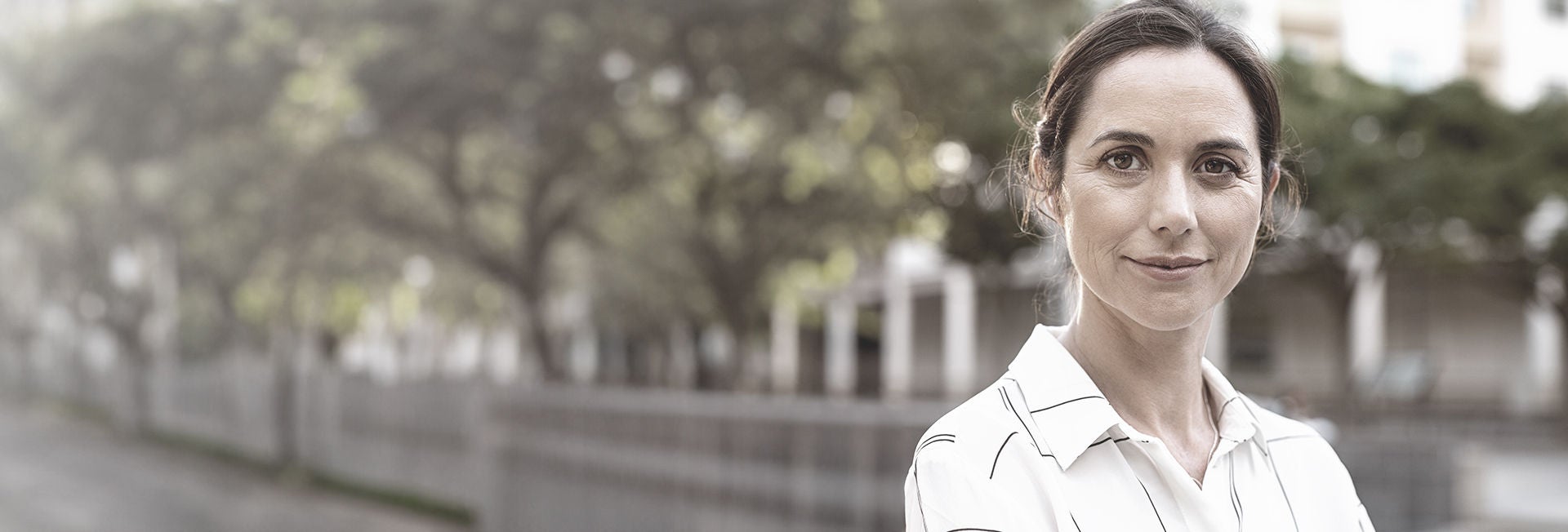 Woman standing outdoors, smiling confidently