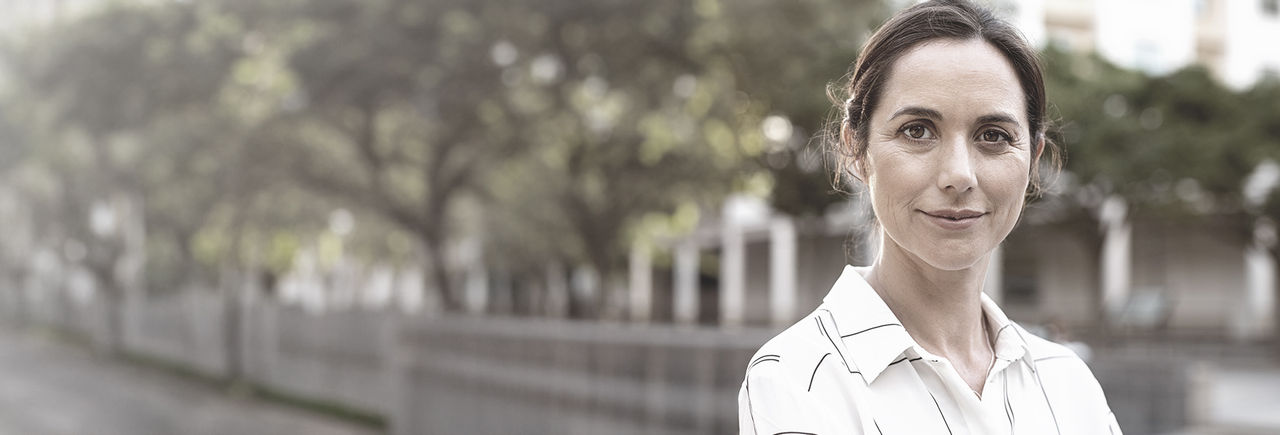Woman standing outdoors, smiling confidently