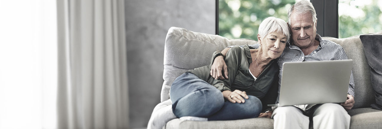 Senior couple at home searching for a pain centre on their computer