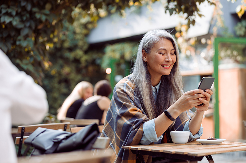 Woman smiling using smartphone at a café